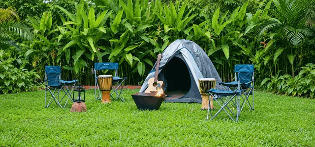 Tent, fire bowl, guitar, drums and camping chairs on the lawn