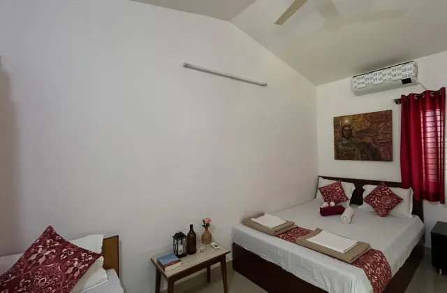 Deluxe AC Cottage — double bed by the red-curtained window