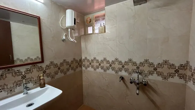 Eco-hut-style dormitory — bathroom with washbasin, geyser and shower taps