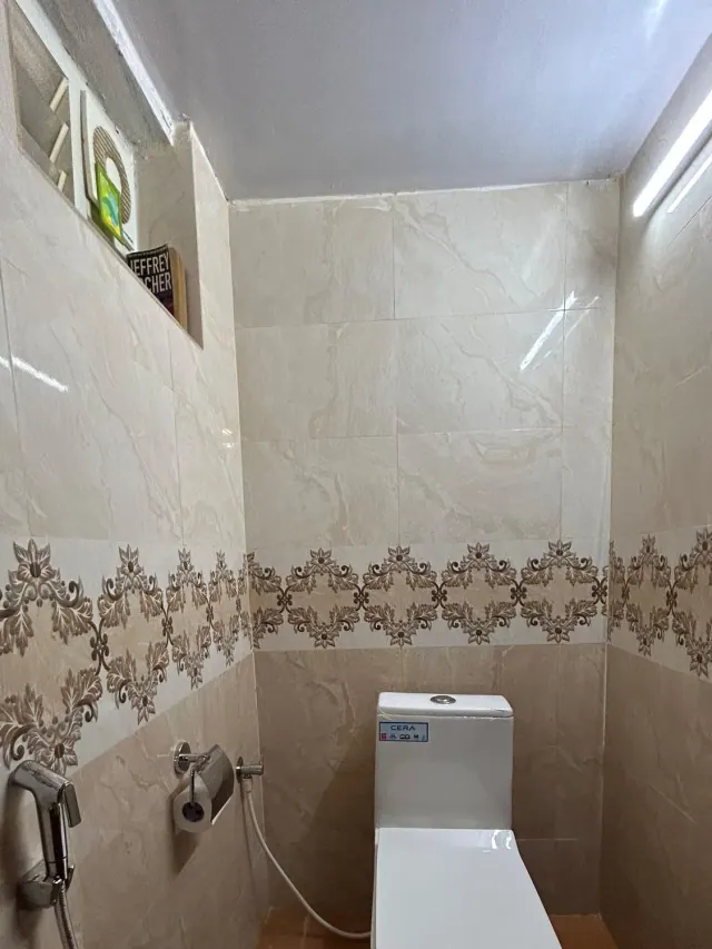 Eco-hut-style dormitory — tiled toilet with a small window shelf