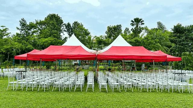 Red canopy tents with rows of white chairs on the lawn