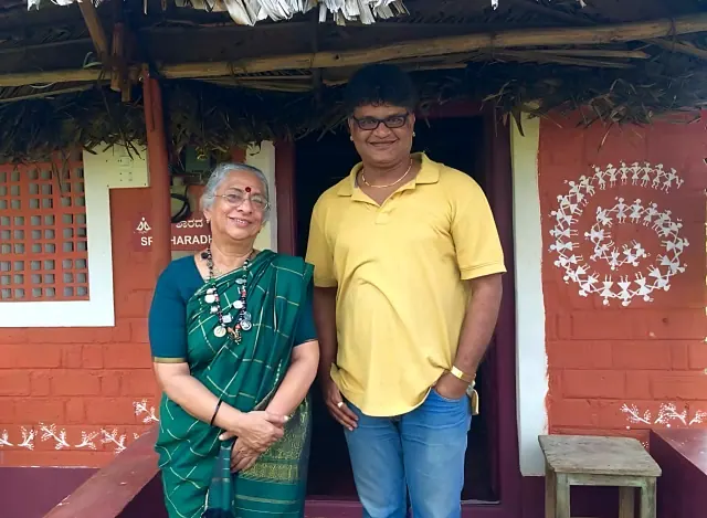 B. Jayashree with founder Prithvi Mallanna outside a painted brick cottage at Saakshi Retreat